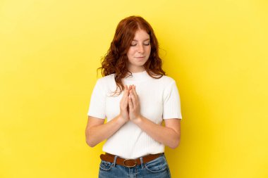 Genç kızılımsı kadın sarı arka planda izole edilmiş bir şeyler çeviriyor.