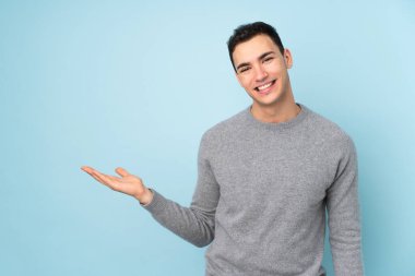 Mavi arka planda izole edilmiş beyaz tenli yakışıklı bir adam.