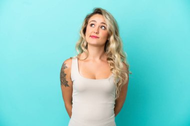 Genç Brezilyalı kadın mavi arka planda izole edilmiş ve yukarı bakıyor.
