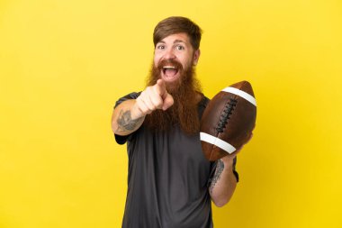 Kızıl saçlı beyaz adam sarı arka planda ragbi oynuyor. 