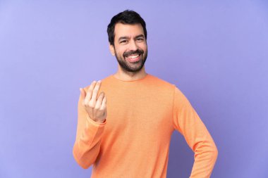 İzole edilmiş mor arka planda beyaz, yakışıklı bir adam. Eli ile gelmesi için davet ediyor. Gelmene sevindim.