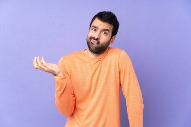 İzole edilmiş mor arka planı olan beyaz yakışıklı bir adam bir şeyi anlamadığı için mutsuz.