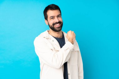 Mavi arka planda beyaz kadife ceketli yakışıklı genç bir adam zaferi kutluyor.