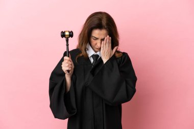 Orta yaşlı yargıç kadın pembe arka planda izole edilmiş, yorgun ve hasta bir ifadeyle.