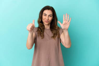 Mavi arka planda izole edilmiş orta yaşlı beyaz kadın parmakları olan altı kişi saydım.