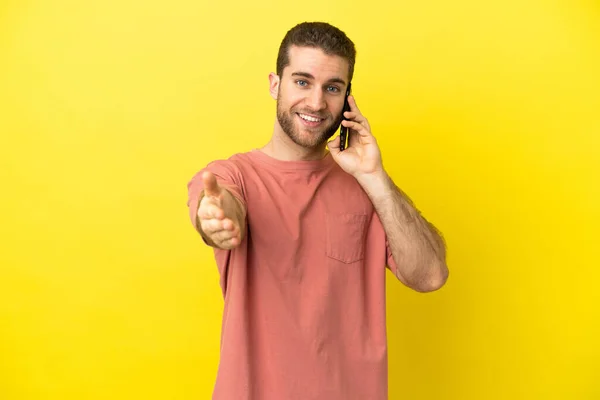 Handsome Blonde Man Using Mobile Phone Isolated Background Shaking Hands — Stock Photo, Image