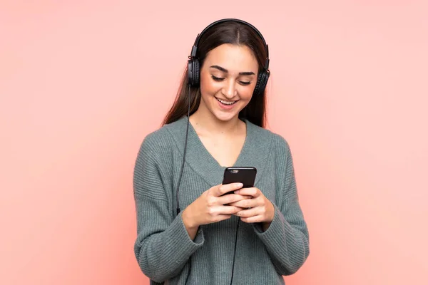 Giovane Donna Caucasica Isolata Sfondo Rosa Ascoltando Musica Guardando Cellulare — Foto Stock