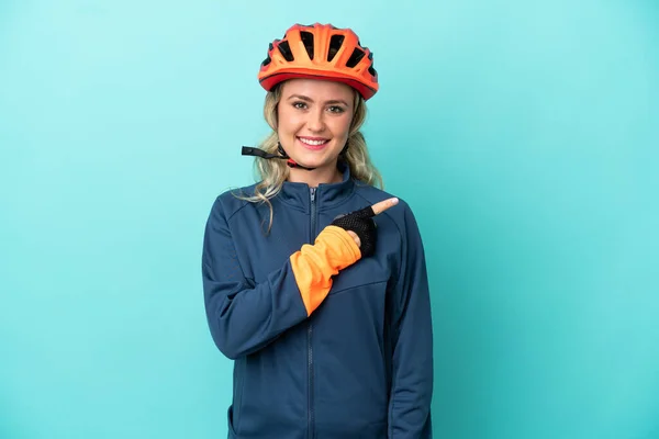Joven Ciclista Mujer Aislada Sobre Fondo Azul Apuntando Hacia Lado —  Fotos de Stock