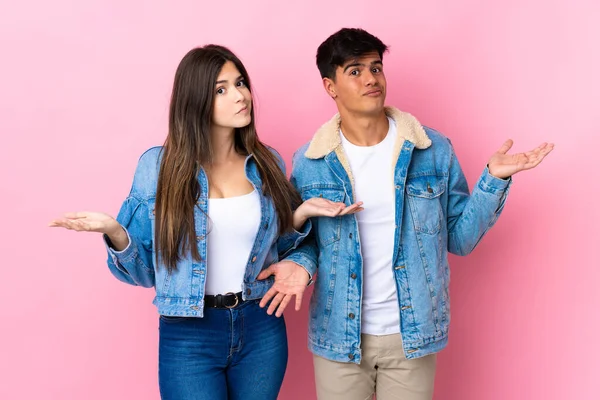 Young Couple Isolated Pink Background Having Doubts While Raising Hands — Stock Photo, Image