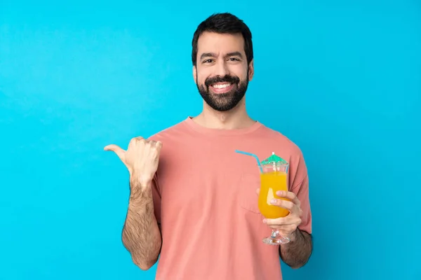 Junger Mann Hält Einen Cocktail Über Einen Isolierten Blauen Hintergrund — Stockfoto