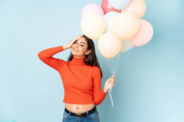 Ung Kvinna Fånga Många Ballonger Isolerade Blå Bakgrund Skrattar — Stockfoto