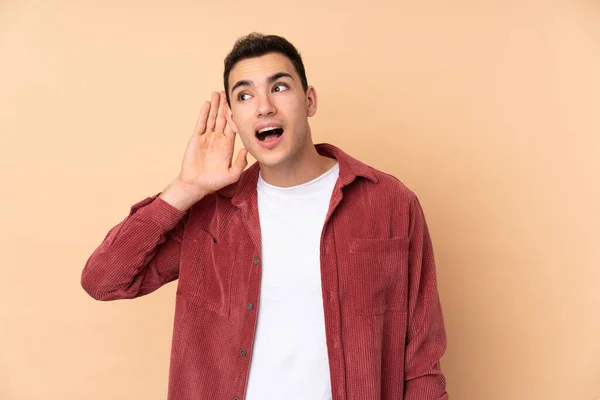 Young Caucasian Handsome Man Isolated Beige Background Listening Something Putting — Stock Photo, Image