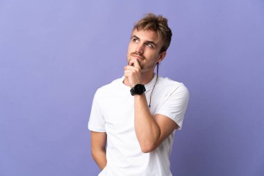 Genç yakışıklı sarışın adam mor arka planda izole edilmiş ve yukarı bakıyor.