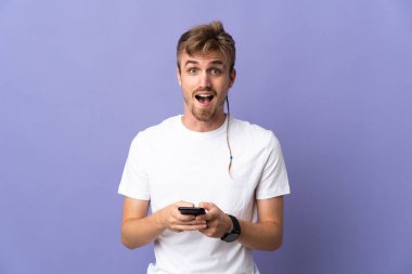 Mor arka planda izole genç yakışıklı sarışın adam şaşırdı ve bir mesaj gönderiyor.