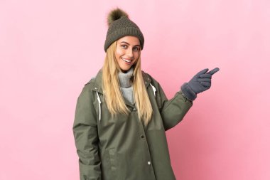 Kış şapkalı genç bir kadın pembe arka planda izole edilmiş.