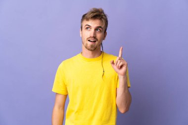 Mor arka planda izole edilmiş genç, yakışıklı sarışın bir adam bir fikir düşünüyor.