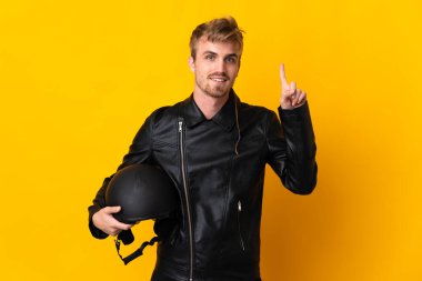 Sarı arka planda izole edilmiş motosiklet kasklı bir adam harika bir fikre işaret ediyor.