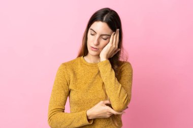 Pembe arka planda izole edilmiş, başı ağrıyan beyaz bir kadın.