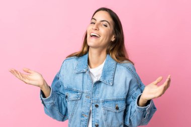 Pembe arka planda izole edilmiş genç beyaz kadın çok gülümsüyor.