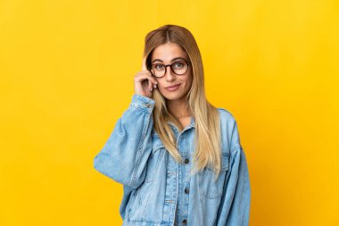 Sarı arka planda izole edilmiş genç sarışın bir kadın bir fikir düşünüyor.