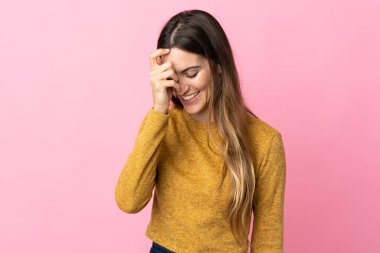 Pembe arka planda izole edilmiş genç beyaz kadın gülüyor.