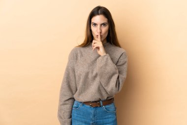 İzole edilmiş arka planda genç beyaz bir kadın sessizce hareket ettiğini gösteriyor. Parmağını ağzına sokuyor.
