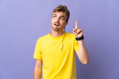 Mor arka planda izole edilmiş genç, yakışıklı sarışın adam parmağını kaldırarak çözümü bulmaya çalışıyor.