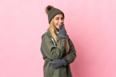 Kış şapkalı genç kadın pembe arka planda izole edilmiş mutlu ve gülümsüyor.