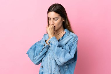 Pembe arka planda izole edilmiş genç beyaz kadın çok öksürüyor.