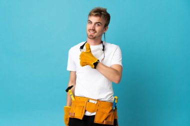 Genç elektrikçi, izole edilmiş duvarın üzerinden baş parmak işareti yapıyor.