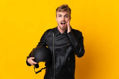 Motosiklet kasklı bir adam sarı arka planda izole edilmiş, şaşırmış ve şok olmuş bir yüz ifadesi var.
