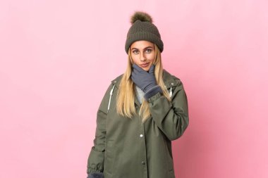 Pembe arka planda izole edilmiş, kış şapkalı genç bir kadın.