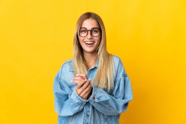 Sarı arka planda yalnız yaşayan genç sarışın kadın gülüyor.