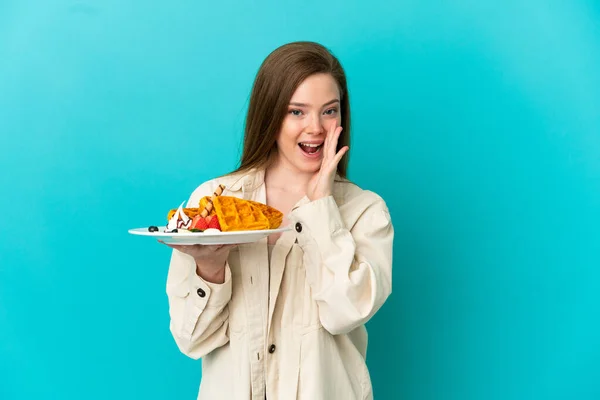 Adolescente Menina Segurando Waffles Sobre Isolado Fundo Azul Gritando Com — Fotografia de Stock