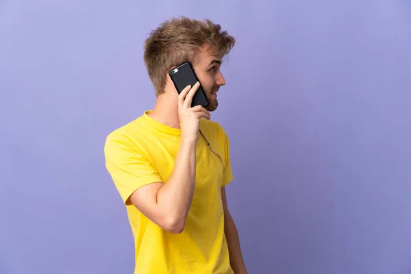 Jovem Homem Loiro Bonito Isolado Fundo Roxo Mantendo Uma Conversa — Fotografia de Stock