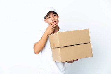 Çinli adam beyaz arka planda izole edilmiş gülümserken yukarı bakıyor.