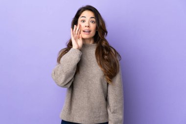 Woman over isolated purple background shouting with mouth wide open