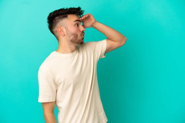 Mavi arka planda mahsur kalmış beyaz bir genç var.