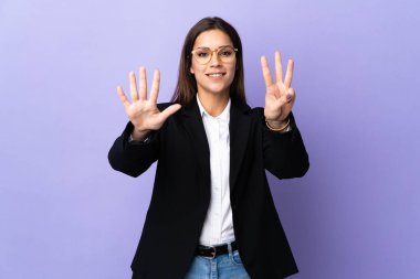 Mor arka planda izole edilmiş iş kadını parmaklarıyla sekiz sayıyor