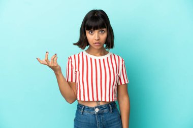 Mavi arka planda izole edilmiş genç melez kadın şüpheli hareketler yapıyor.