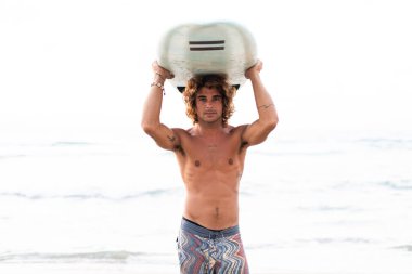 Kafkasyalı genç adam gün doğumunda sörf yapmak için erken kalkar.