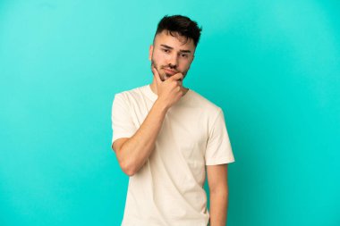 Kafkasyalı genç adam mavi arka planda soyutlanmış düşünüyor.