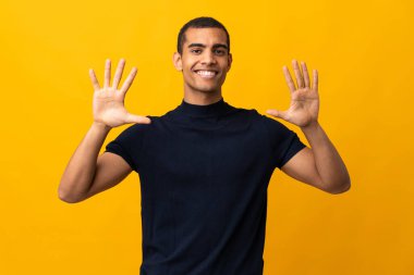 İzole edilmiş sarı arka planda sayıları sayan Afrikalı Amerikalı bir adam.