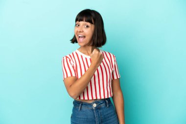 Mavi arka planda izole edilmiş genç melez kadın zaferi kutluyor.