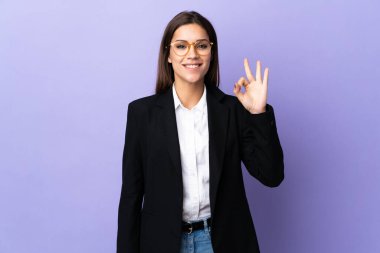 Mor arka planda izole edilmiş iş kadını parmaklarıyla tamam işareti gösteriyor