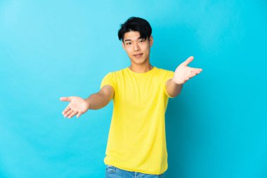 Mavi arka planda izole edilmiş genç bir Çinli sunar ve davet eder.