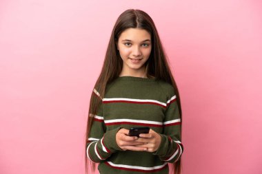 Pembe arka planda küçük bir kız cep telefonuyla mesaj gönderiyor.
