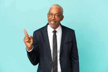 İşletme son sınıf öğrencisi mavi arka planda izole edilmiş bir şekilde bir ürün sunmak için kenarı işaret ediyor