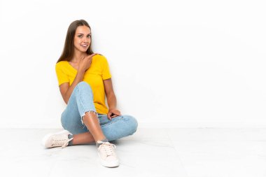 Genç kız yerde oturuyor ve parmağını yana doğru gösteriyor.