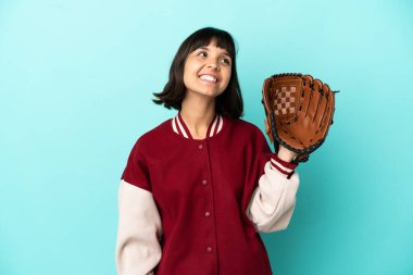 Beyzbol eldivenli, genç, melez bir kadın. Mavi arka planda izole edilmiş, yukarı bakarken bir fikir düşünüyor.